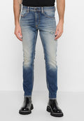 Schmale Jeans aus Denim in einem verblassten Blau, mit einem distressed Patch und kontrastierenden Nähten. Kombiniert mit glänzenden schwarzen Knöchelstiefeln.