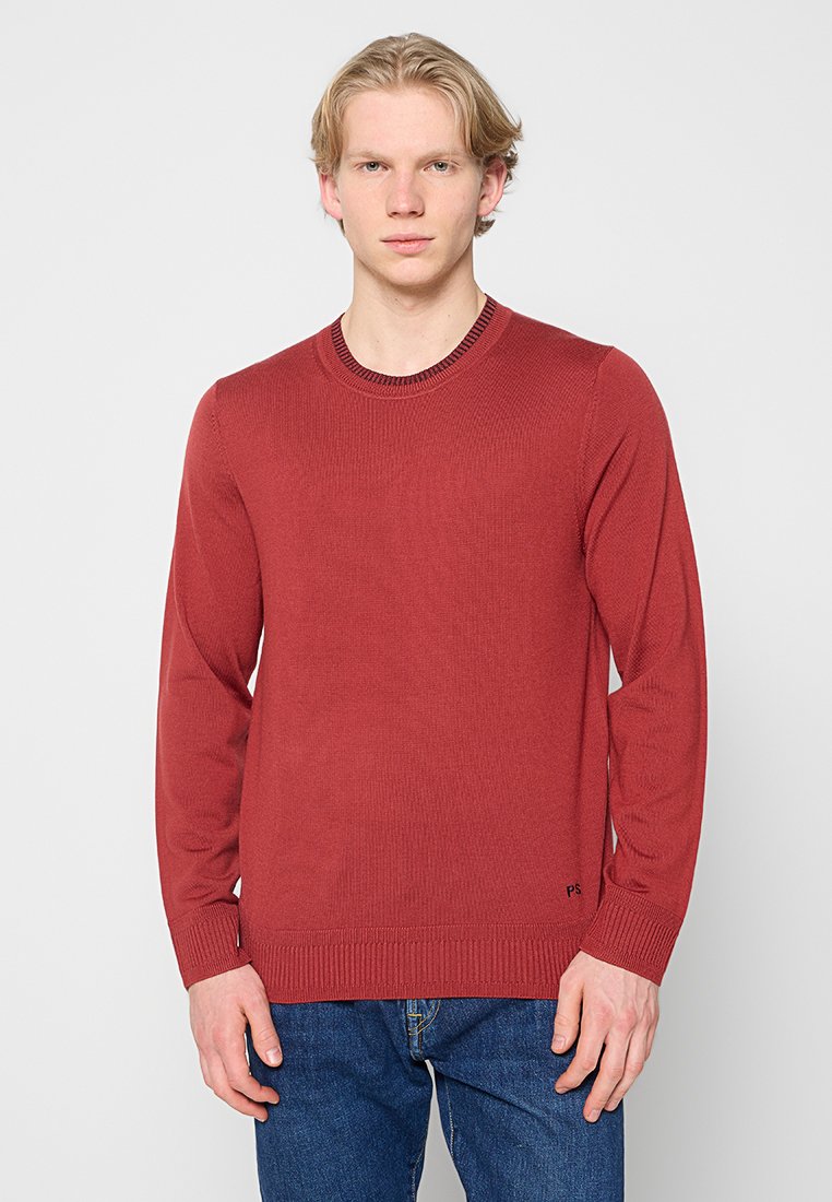 Roter gestrickter Pullover mit rundem Ausschnitt, langen Ärmeln sowie gerippten Bündchen und Saum. Verfügt über ein kleines schwarzes Logo unten links.