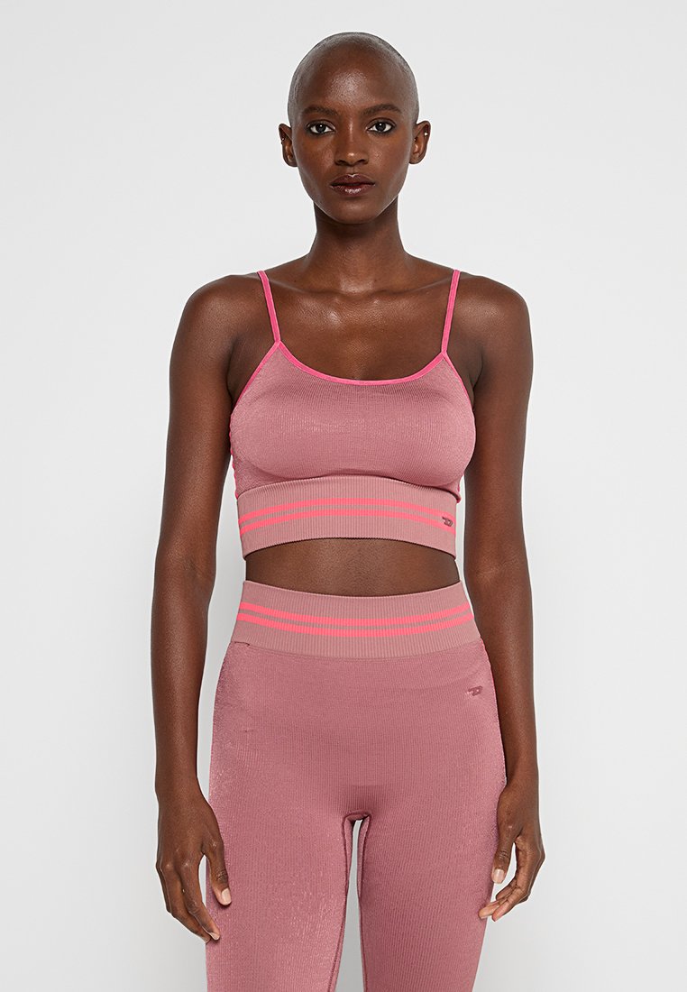Rosa gerippter Sport-BH mit dünnen Trägern, der leuchtend pinke Akzente entlang des Ausschnitts und des Saums aufweist, kombiniert mit passenden hochtaillierten Leggings.