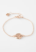 Roségold-Armband mit einem runden Anhänger, der ein Logo und Kristallakzente zeigt, verbunden durch eine zarte Kette mit einem Verschluss.
