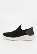 Schwarze Slipper mit Textiloberfläche, gepolstertem Schaft und einer weißen, strukturierten Gummisohle. Akzente umfassen einen Logotag.