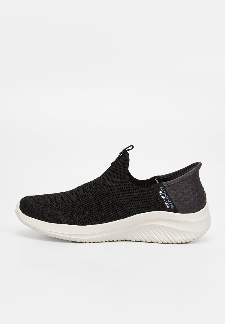 Schwarze Slipper mit Textiloberfläche, gepolstertem Schaft und einer weißen, strukturierten Gummisohle. Akzente umfassen einen Logotag.