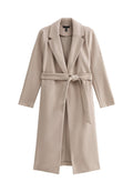 Beige langer Mantel aus weichem Material, mit Reverkragen, offenem Frontbereich und einem gebundenen Taillengürtel. Glattes, unstrukturiertes Gewebe.