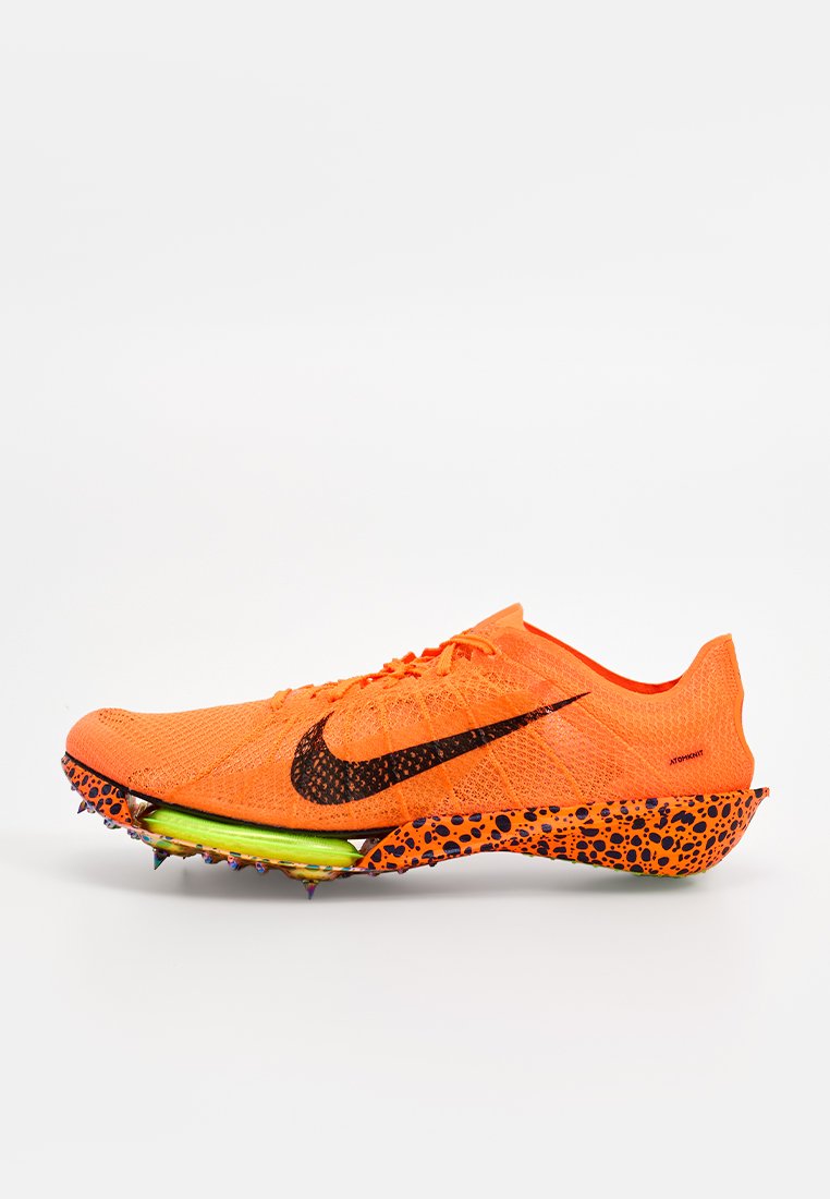 Nike-Laufschuh mit einem leuchtend orangefarbenen Obermaterial aus Mesh, schwarzem Swoosh-Logo, grüner Zwischensohle und punktemusterter Außensohle in Orange und Lila.