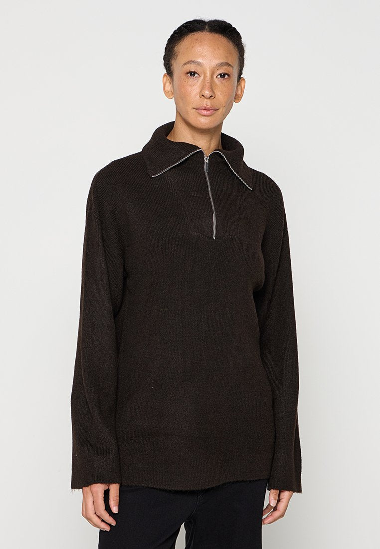 Brauner Strickpullover mit hohem Kragen und halbem Reißverschluss. Verfügt über lange Ärmel und Seitenschlitze am Saum. Weiche Textur, lockere Passform.
