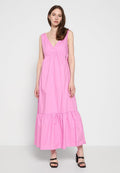 Rosa Baumwoll-Maxikleid mit V-Ausschnitt, ärmellosem Design und mehrlagigem rüschengesäumtem Saum. Kombiniert mit schwarzen Blockabsatzsandalen.