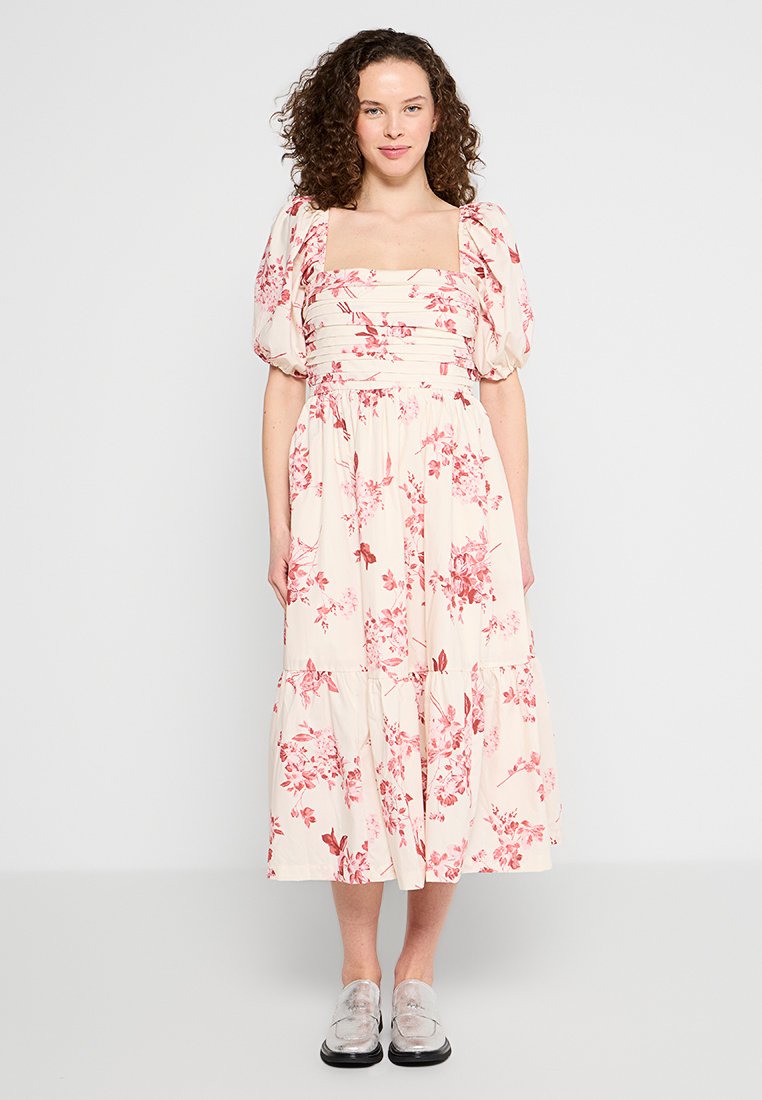 Blumenkleid in Creme mit rosa und roten Mustern, das puffärmel und einen quadratischen Ausschnitt sowie einen schichtweisen, gerafften Rock hat.