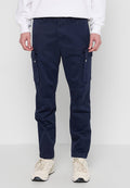 Marine Cargo-Hose aus Baumwolle, mit seitlichen Taschen mit Reißverschlüssen, schlanker Passform und leichtem Stretch. Getragen mit hellen Sneakers.