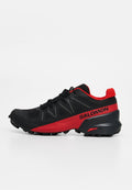 Schwarz-rote Salomon Trail-Laufschuhe mit Schnürsenkeln, robuster Sohle und Logo an der Seite vor weißem Hintergrund.