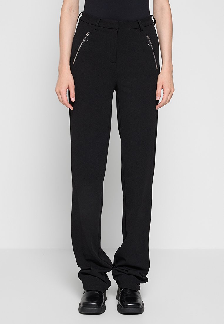 Schwarze Hose mit geradem Schnitt, ausgestattet mit einem Gürtel, zwei vorderen Reißverschlusstaschen und einem glatten, strukturierten Stoff.