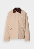 Beige Jacke mit einem braunen Samtkragen, mit einem Druckknopfverschluss, zwei seitlichen Taschen und einem kleinen Logopatch auf der Brust.