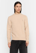 Beiger Strickpullover mit rundem Halsausschnitt sowie gerippten Bündchen und Saum. Verfügt über ein kleines Logo auf der Brust. Das Model trägt dunkle Jeans.