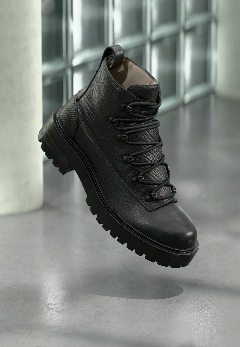 Schwarze Leder-Stiefeletten mit strukturiertem Obermaterial, sechs Ösen und einer robusten Sohle. Mit einer Fersenschlaufe für einfaches An- und Ausziehen.