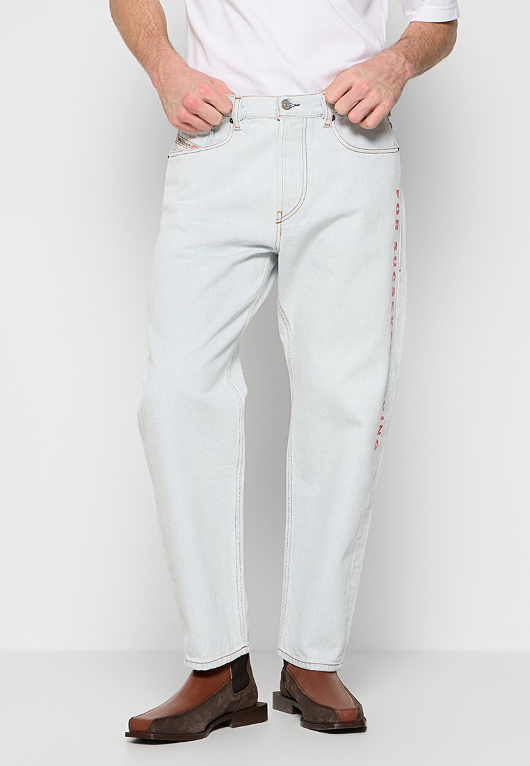 Hellblaue Jeans aus Denim mit lockerer Passform, versehen mit kontrastierenden Nähten und rotem Text an der Seite. Das Material hat eine glatte Textur.