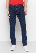 Dunkelblaue Jeans aus Denim mit geradem Schnitt, ausgestattet mit einem klassischen Fünf-Taschen-Design und dezenten Nähdetails. Getragen mit weißen Slippern.