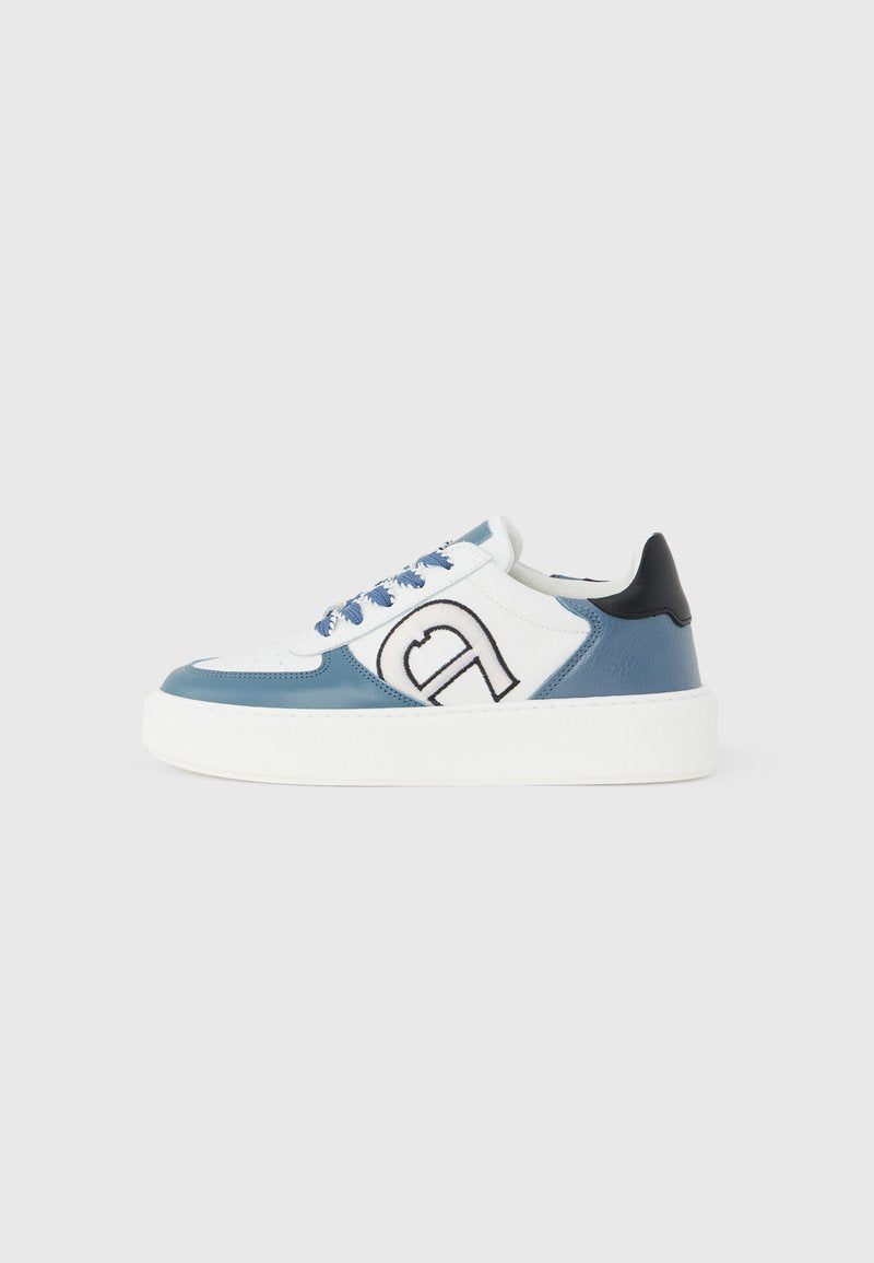 Weiß-blauer Sneaker mit niedrigem Schnitt, schwarzem Fersenlasche, grau-blauen Schnürsenkeln, dicker weißer Sohle und großem schwarz umrandetem Logo auf dem Seitenpanel.