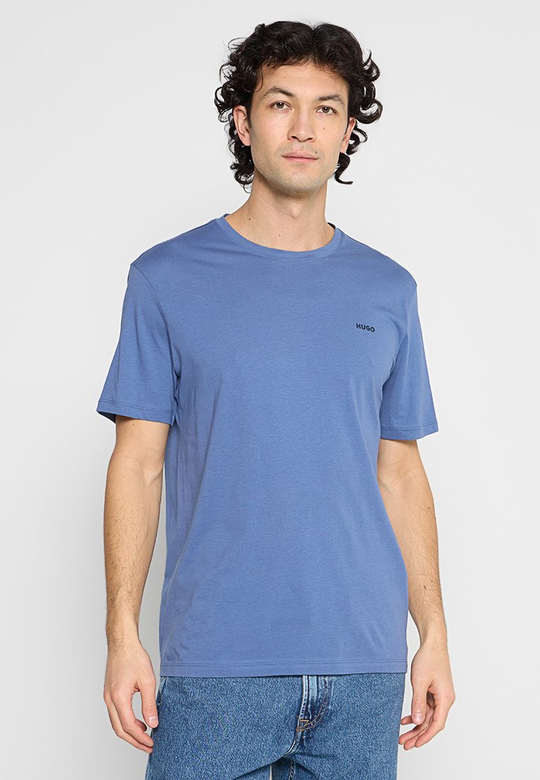 Baumwoll-T-Shirt in Blau mit Rundhalsausschnitt und kurzen Ärmeln. Mit einem kleinen schwarzen Logo auf der Brust. Glatte Textur, normale Passform.