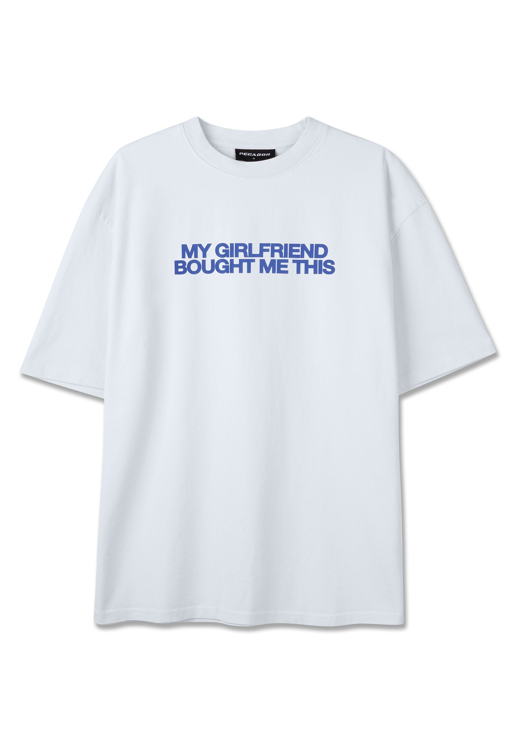Weißes T-Shirt mit kurzen Ärmeln und blauem Text zentriert auf der Brust, der in fetten Großbuchstaben "MEINE FREUNDIN HAT MIR DAS GEKAUFT" lautet.