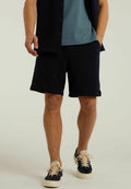 Marineblaue Shorts mit glatter Textur, Seitentaschen und einem elastischen Bund, kombiniert mit einem türkisfarbenen Rundhals-Shirt und marineblauen Sneakers.