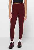 Burgunderfarbene gemusterte Leggings mit hohem Bund, aus strukturiertem Stoff, kombiniert mit schwarzen Sportschuhen und weißen Socken.