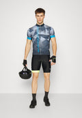 Radbekleidung mit einem grauen geometrischen Muster auf dem Trikot, blauen Akzenten und schwarzen Shorts mit gelbem Saum, ergänzt durch einen schwarzen Helm.