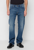 Helle blaue Denim-Jeans, gerader Schnitt, fünf Taschen Design, kontrastierende Nähte, Knopf- und Reißverschluss, getragen über schwarzen Schuhen.