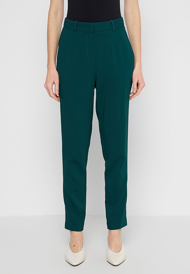 Grüne, maßgeschneiderte Hose mit glatter Textur, schlanker Passform, konisch zulaufenden Beinen und mittelhohem Taillenbund. Akzentuiert mit vorderen Nähten und Taschen.