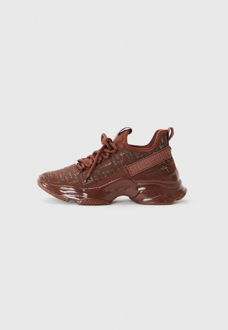 Braune Sportschuhe mit einer strukturierten Strick-Oberfläche, Schnürdesign und glänzender Sohle, die abstrakte Muster und ein seitliches Logo-Detail aufweist.