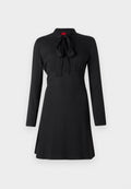Schwarzes Kleid mit langen Ärmeln, einem hohen Kragen und einer Schleifen-Detail am Ausschnitt. Glattes Material mit eng anliegendem Oberteil und ausgestellt Rock.