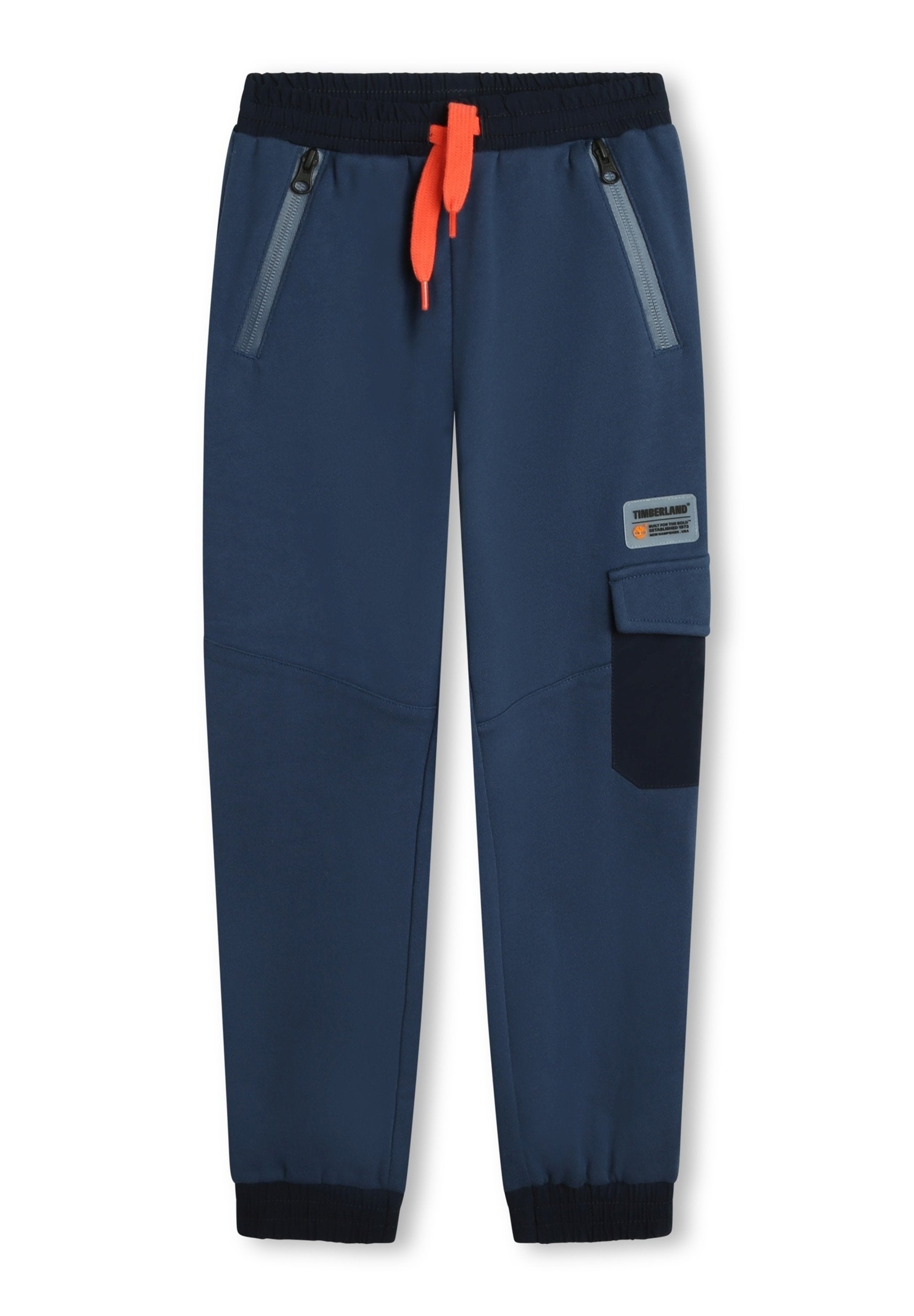 Marinefarbene Jogginghosen mit elastischem Bund, orangefarbigem Kordelzug, seitlichen Reißverschluss-Taschen und einer aufgesetzten Tasche am linken Bein. Glattes Material und schmal zulaufende Bündchen.
