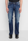 Mann trägt dunkelblaue Jeans mit geradem Bein und verblassten Details, schwarze Lederschuhe und ein schwarzes Hemd vor einem schlichten weißen Hintergrund.