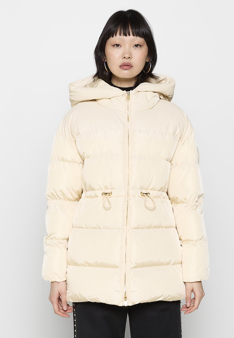 Puffjacke in hellem Beige, mit Kapuze, Reißverschluss, elastischen Kordeln und goldenen Hardware-Akzenten. Glatte, gepolsterte Textur.