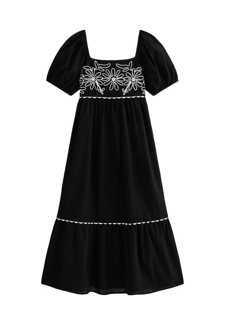 Schwarzes Kleid mit kurzen Puffärmeln, quadratischem Ausschnitt, weißer Blumenstickerei auf dem Oberteil und einem gestuften Rock mit welligem Saum.