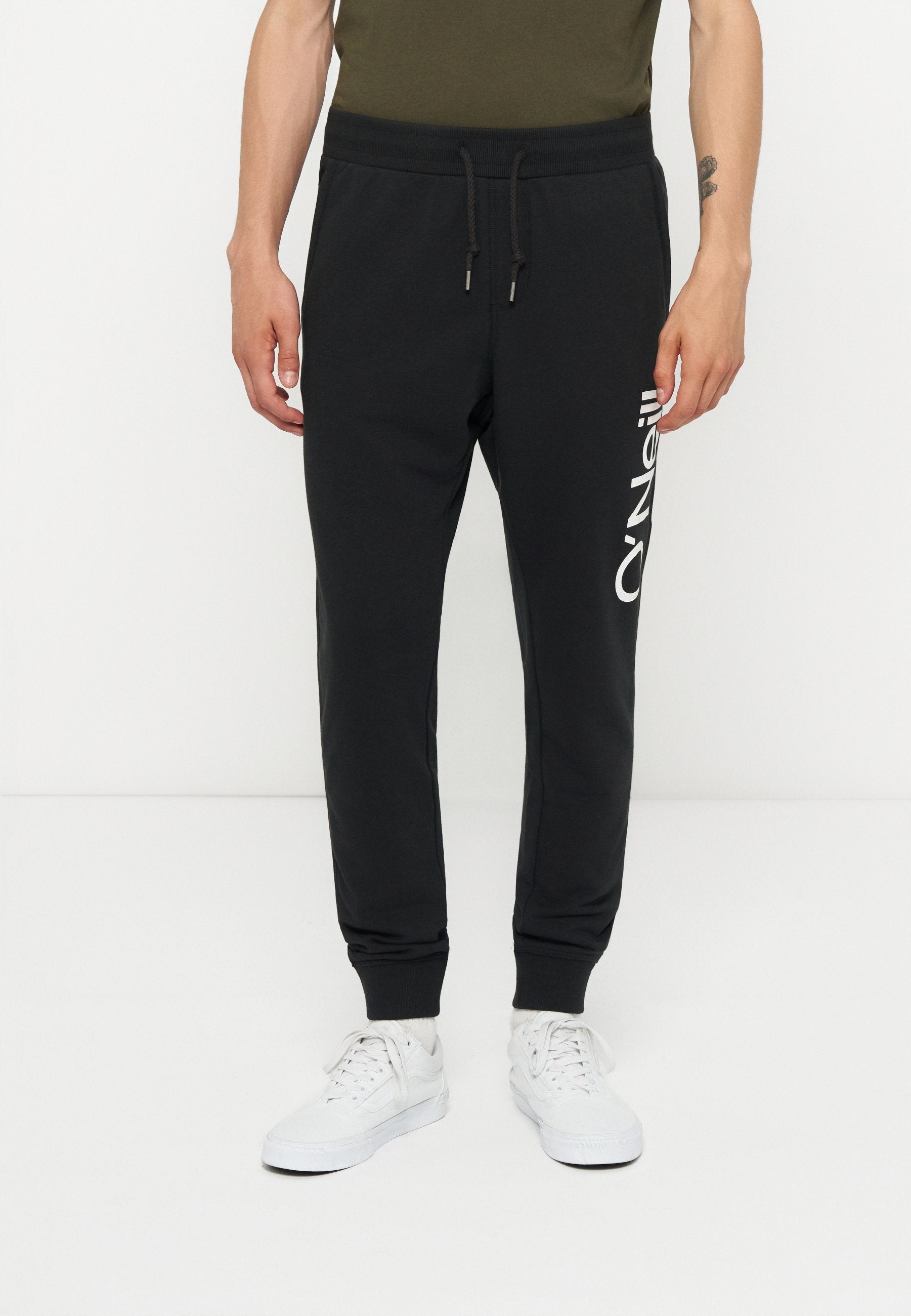 Mann trägt schwarze Jogger-Hose mit weißem O'Neill-Logo am linken Bein und weiße Sneaker, steht vor einem schlichten weißen Hintergrund.