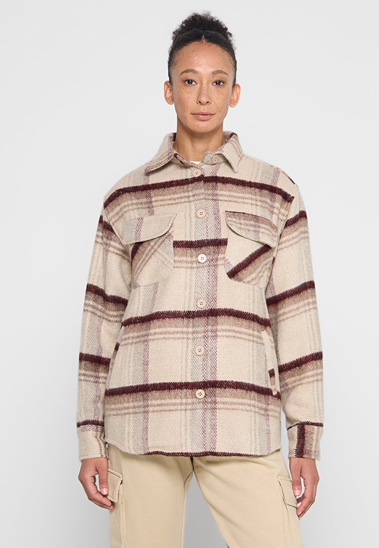 Beige Flanellhemdjacke mit kariertem Muster in Bordeauxrot und Braun, ausgestattet mit zwei Brusttaschen und Knopfverschluss. Weicher Stoff und lässige Passform.