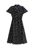 Schwarzes Kleid mit weißen Pünktchen, kurzen Ärmeln, Knopfverschluss vorne, gebundenem Taillenbund und weiter Rock. Weicher Stoff mit glatter Textur.
