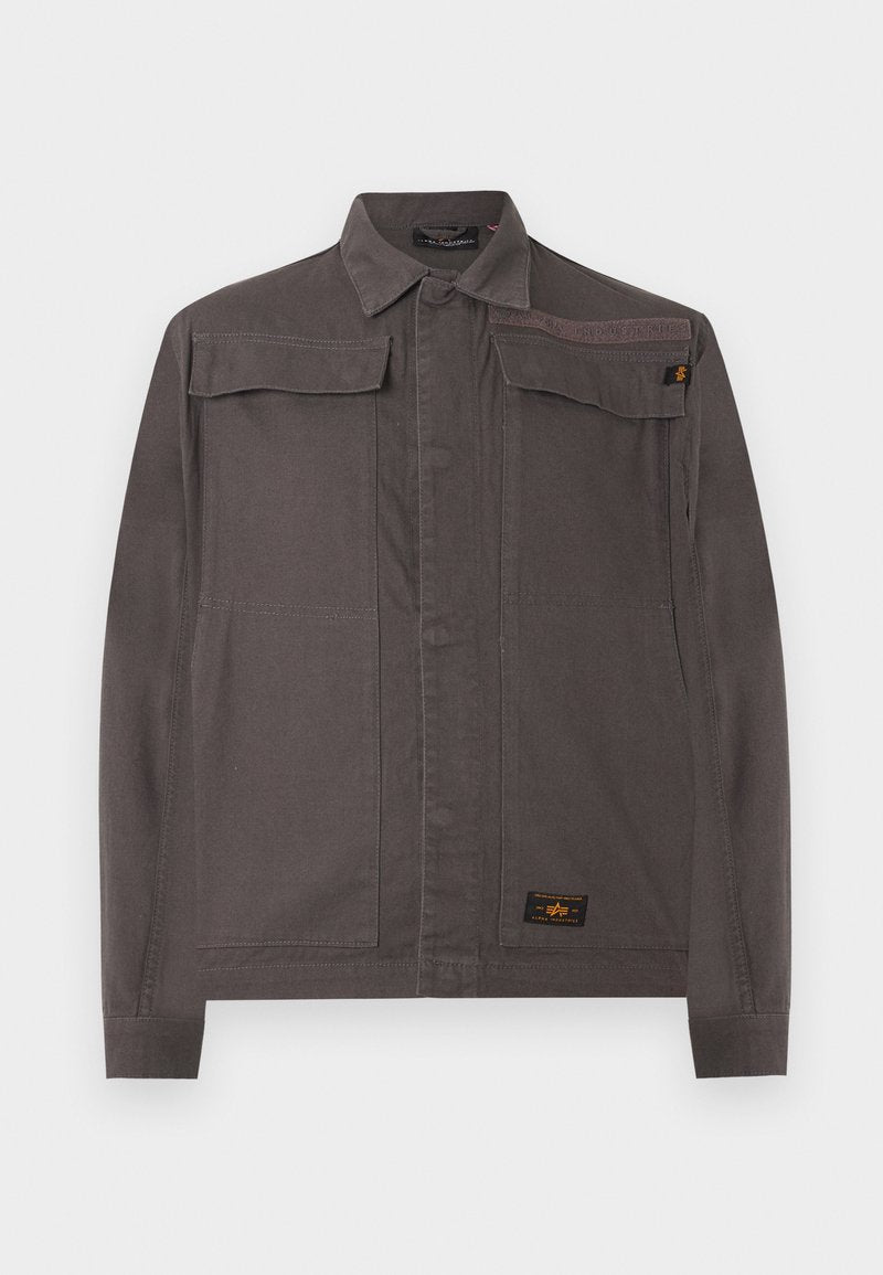 Dunkelgraue Freizeitjacke mit langen Ärmeln, Kragen, zwei Brustklappentaschen und einem Markenetikett nahe dem Saum vor weißem Hintergrund.
