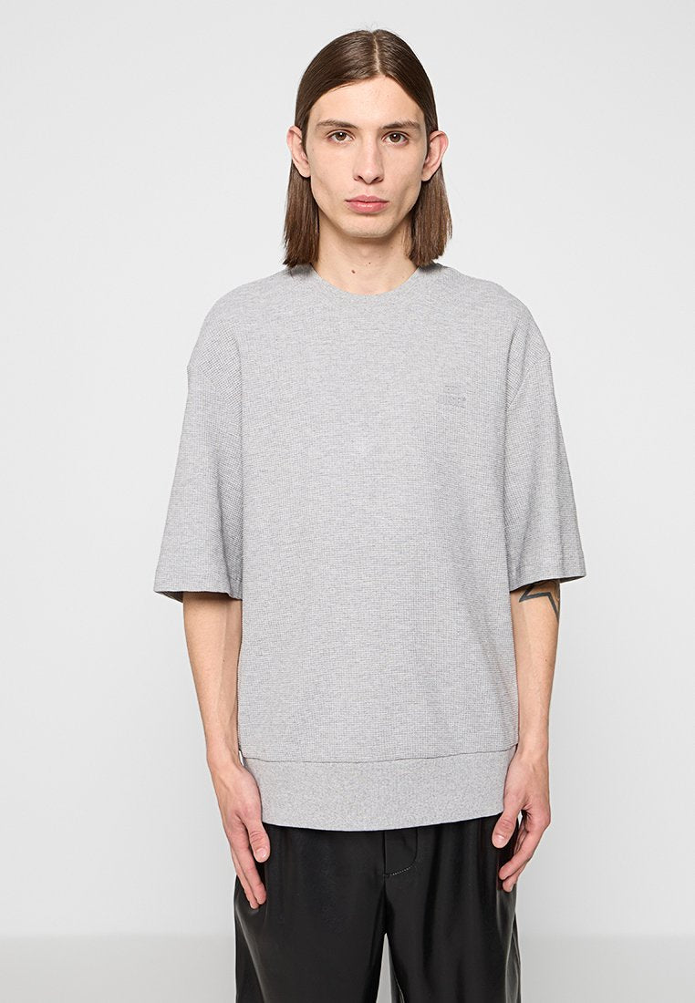 Graues, übergroßes T-Shirt aus strukturiertem Strick, mit Rundhalsausschnitt und kurzen Ärmeln. Der untere Saum ist leicht gerippt.