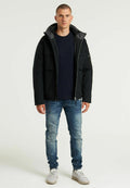 Schwarze Kapuzenjacke mit Reißverschluss, mehreren Taschen und grauem Innenfutter. Kombination mit einem marineblauen Shirt, verwaschenen blauen Jeans und Turnschuhen.