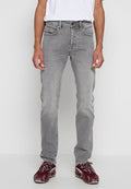 Graue Denim-Jeans mit geradem Schnitt, fünf Taschen und Metallknopfverschluss. Kombiniert mit einem weißen T-Shirt und weinroten Sneakers.