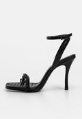 Schwarze Lackleder-High-Heel-Sandale mit dünnem Knöchelriemen, quadratischer Zehenpartie, gepolstertem Textur und Kettendetail an der Vorderseite.