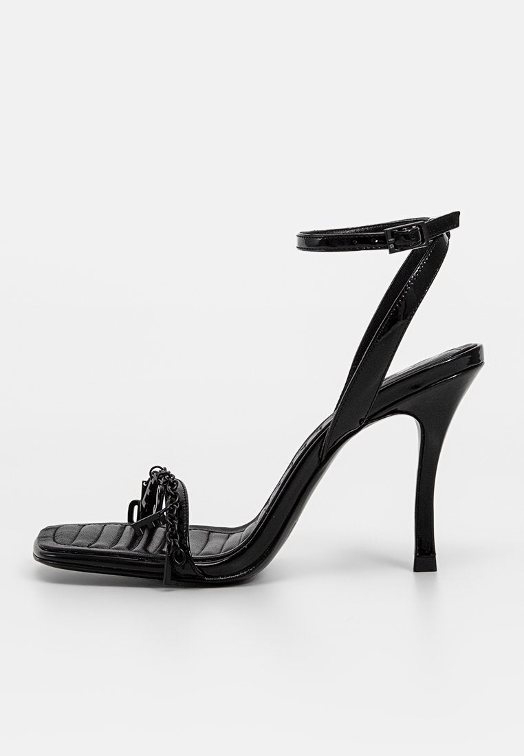 Schwarze Lackleder-High-Heel-Sandale mit dünnem Knöchelriemen, quadratischer Zehenpartie, gepolstertem Textur und Kettendetail an der Vorderseite.
