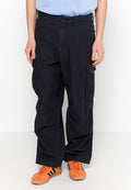 Mann in lässigen schwarzen Cargo-Hosen und leuchtend orangen Sneakers mit schwarzen Streifen, der vor einem weißen Hintergrund steht.