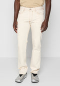 Beige Baumwolljeans mit geradem Bein, kontrastierenden orangen Nähten und Fünf-Taschen-Design, getragen mit silbernen Slip-On-Schuhen.