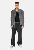 Grau gefütterte Kunstfelljacke, geripptes schwarzes Top, lockere schwarze Hose mit einem Stoffgürtel und sneakers mit metallischem Muster.