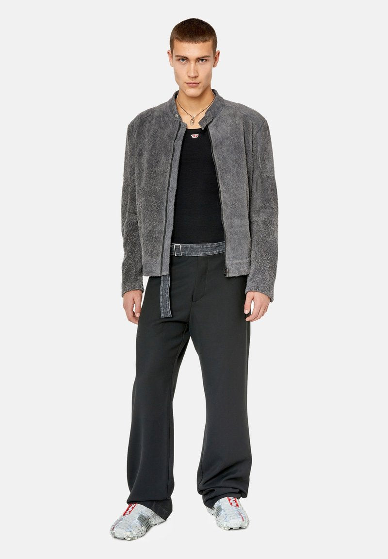 Grau gefütterte Kunstfelljacke, geripptes schwarzes Top, lockere schwarze Hose mit einem Stoffgürtel und sneakers mit metallischem Muster.