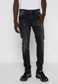 Schwarze Denim-Jeans mit slim Fit, die leicht verwaschen und dezent gefädelt sind. Abgeschlossen mit einem Knopfverschluss und seitlichen Taschen.