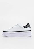 Weißer Plateau-Sneaker mit glattem Lederobermaterial, schwarzem, strukturiertem Fersenakzent mit Strasssteinen und weißer Gummisohle mit schwarzem Streifen.