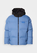 Hellblauer Pufferjacke mit schwarzer Kapuze, vorderem Reißverschluss und horizontalen Nähten. Mit blauem Logo auf der linken Brustseite.