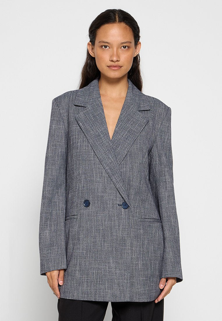 Doppelt gefütterte Blazer aus strukturiertem grauem Stoff mit spitzen Revers und zwei marineblauen Knöpfen, ausgestattet mit seitlichen Taschen und einer taillierten Passform.